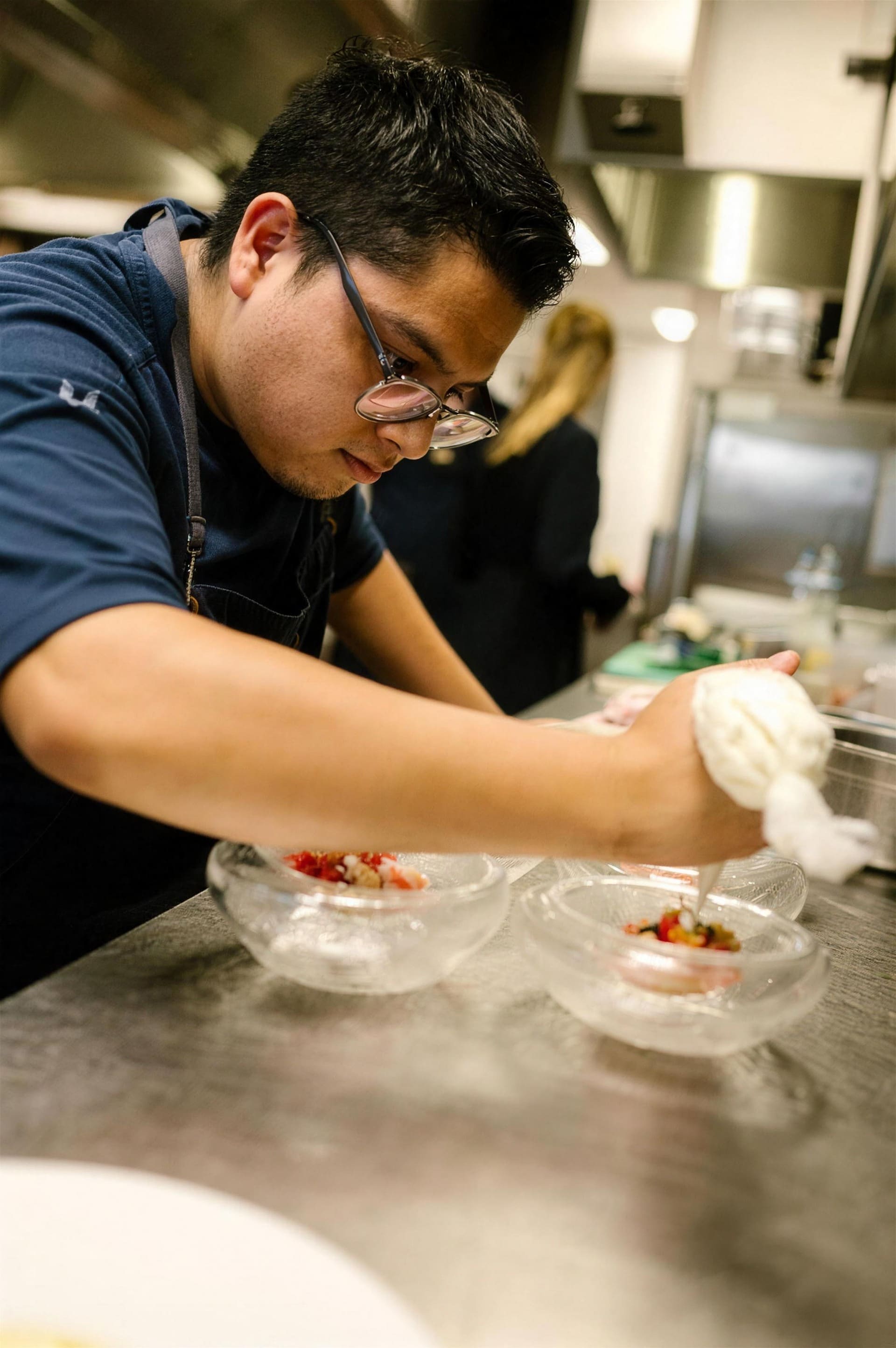 Een kok van Prix de Rome werkt geconcentreerd een gerecht af in de keuken