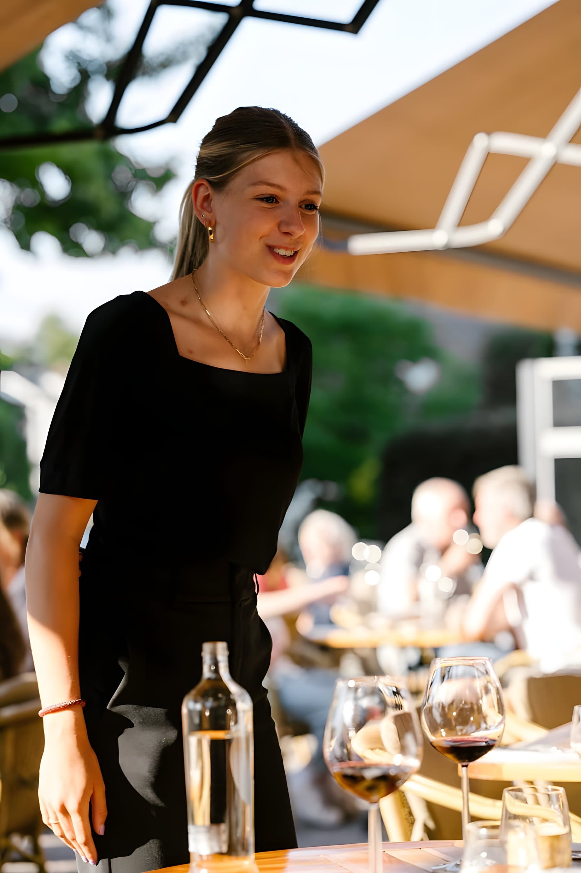 Gastvrouw van Prix de Rome op het terras, tussen de gedekte tafels